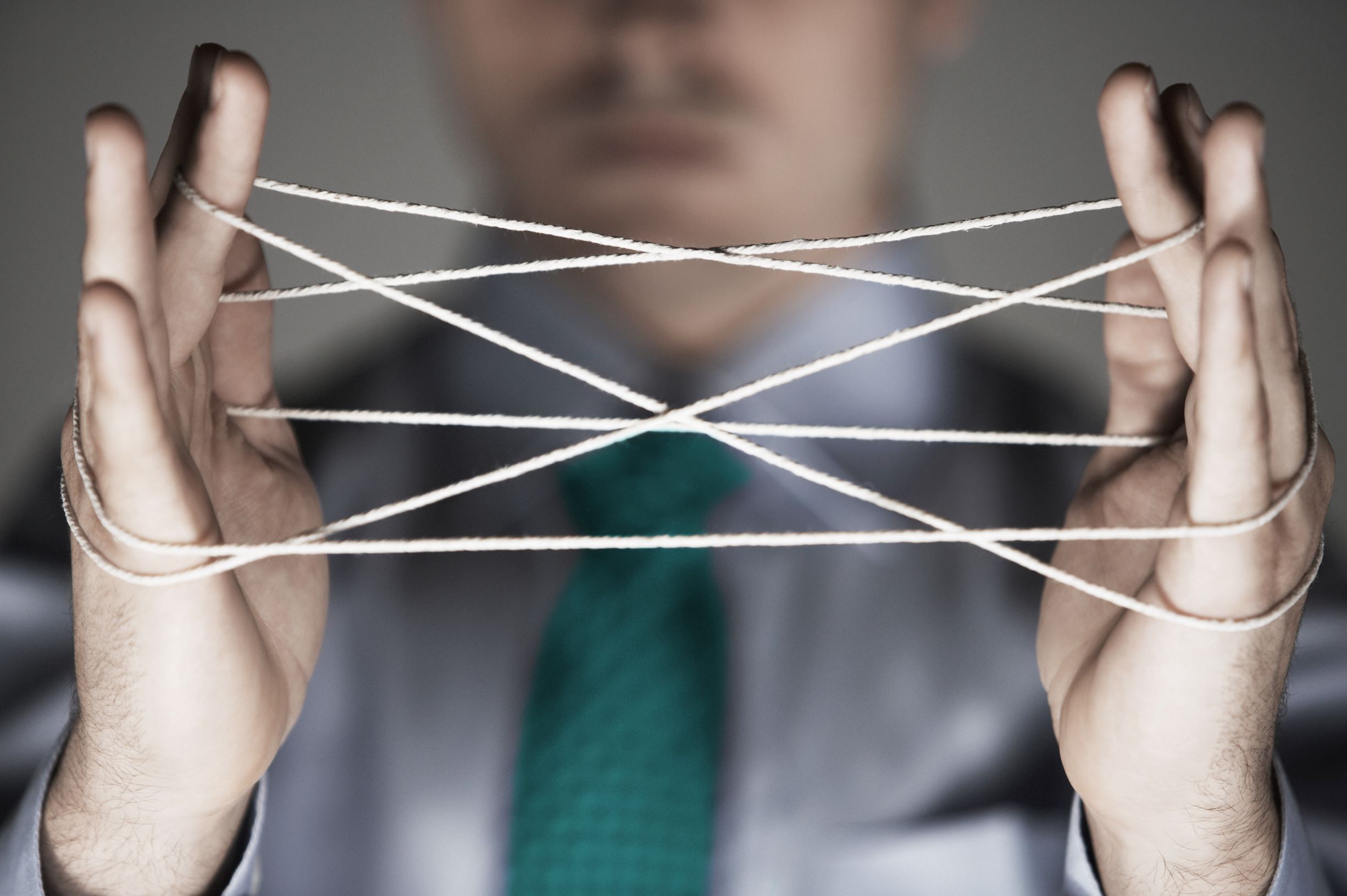 Businessperson holding a complex string figure, symbolising the intricate legal considerations around employer liability for sexual harassment outside work.