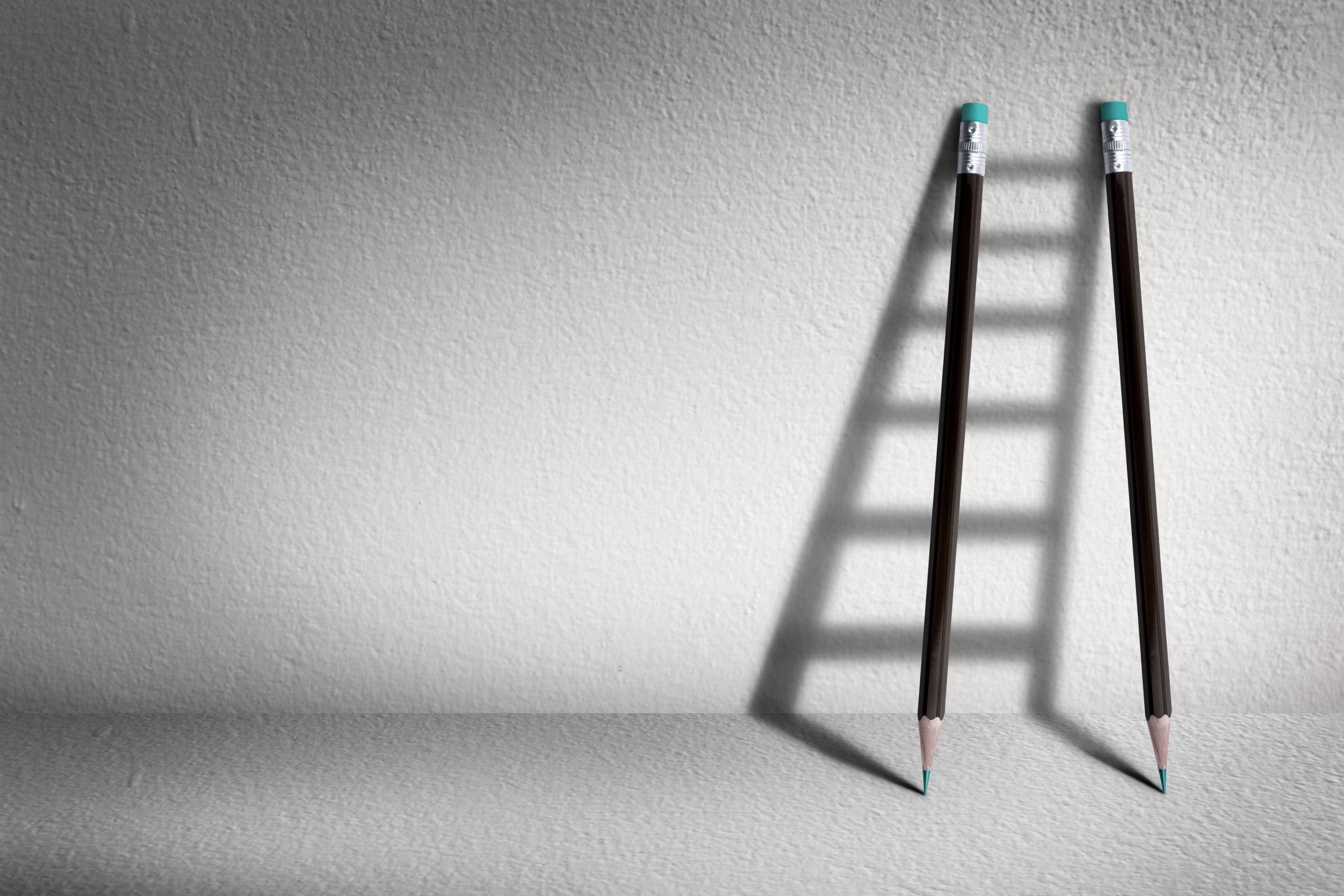 Two pencils casting a shadow shaped like a ladder, symbolizing steps toward compliance with the Employment Rights Bill 2025